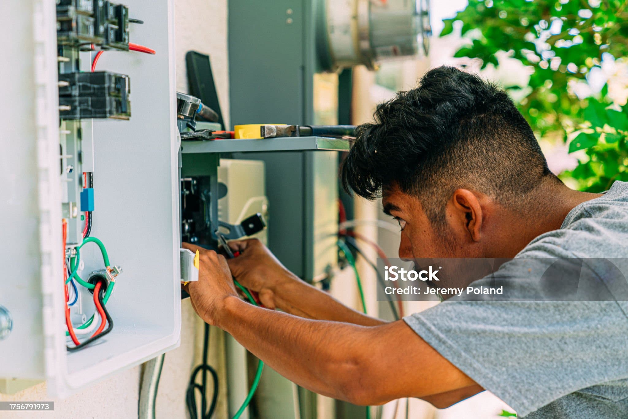 An electrician working on an outdoor residential electrical panel