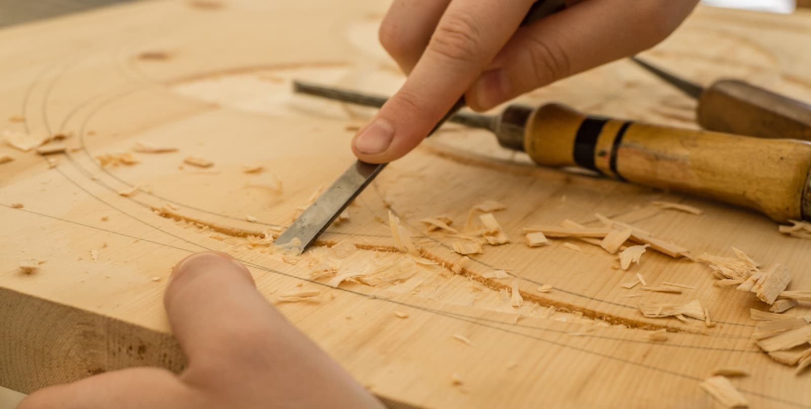 A pair of hands shaping wood with a chisel