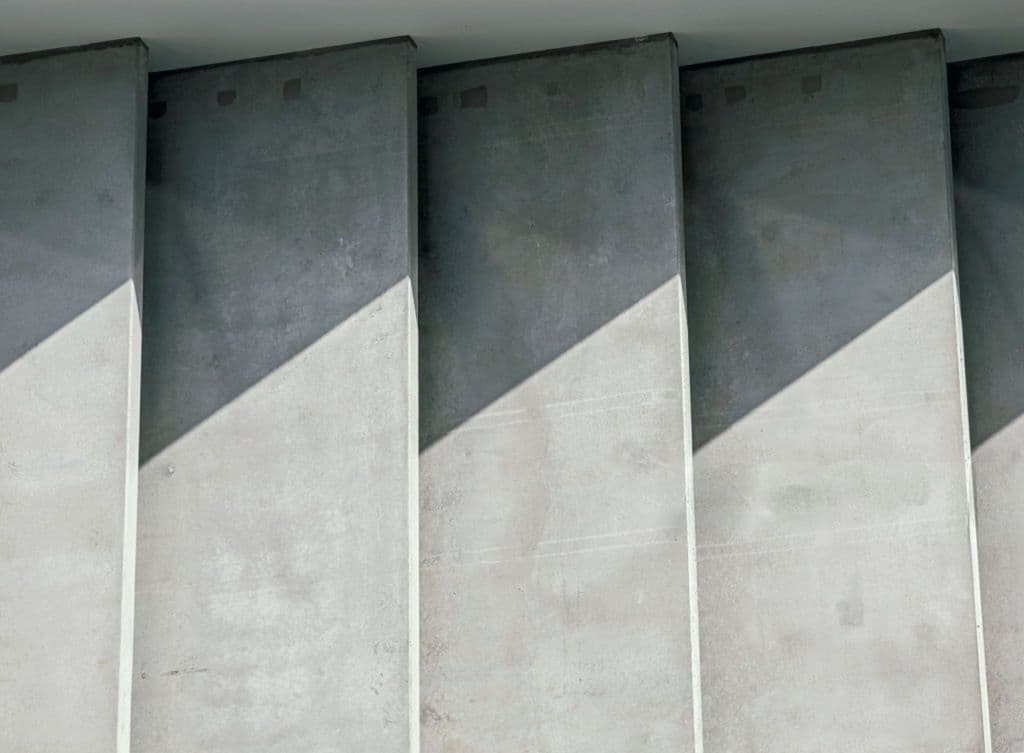 Rhythmic concrete fins cut by a hard diagonal shadow