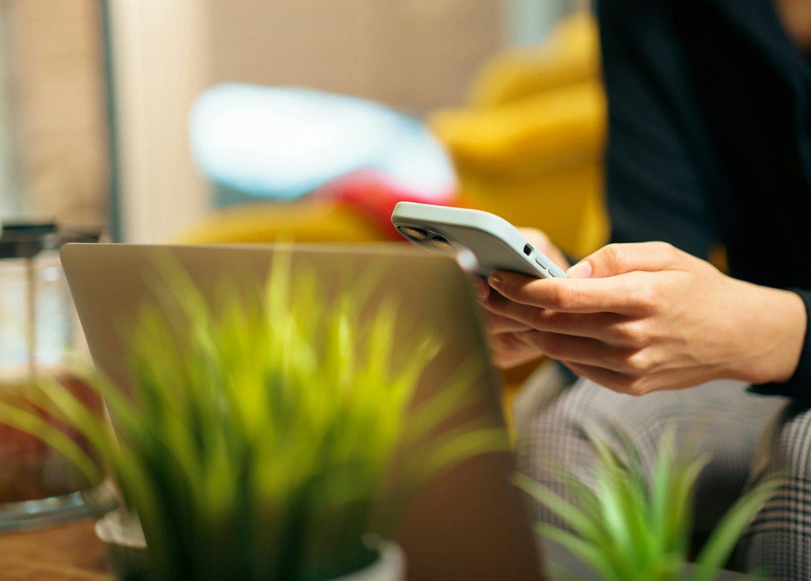 Someone using a phone next to an open laptop on a desk