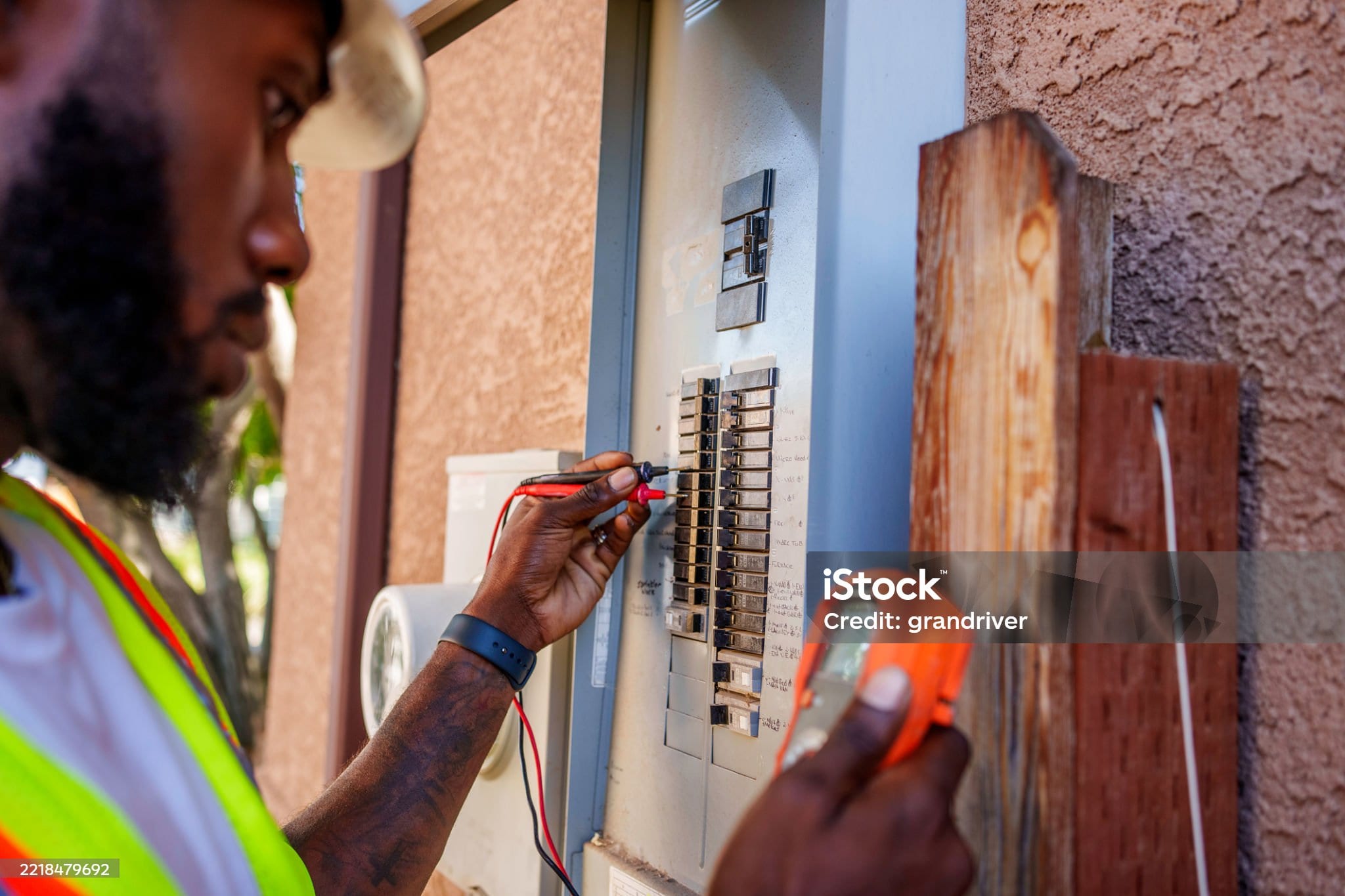 An electrician testing circuits in a hand-labelled residential panel on a service call