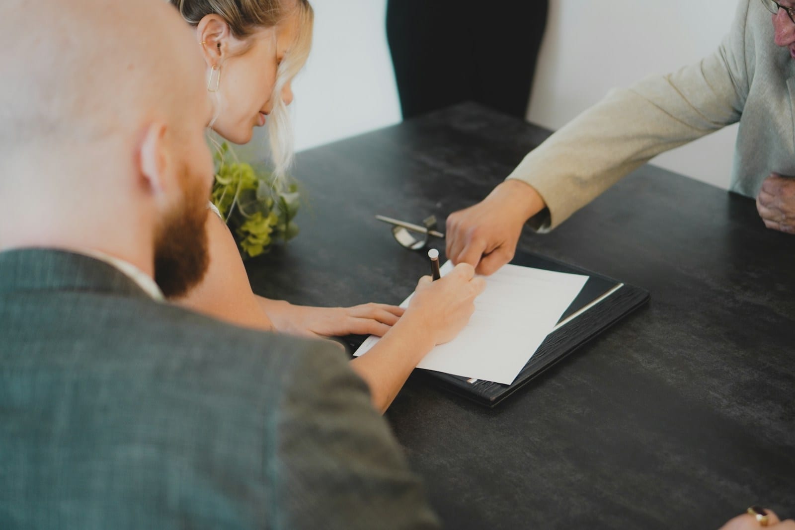 A couple signing a document at a desk with a pen