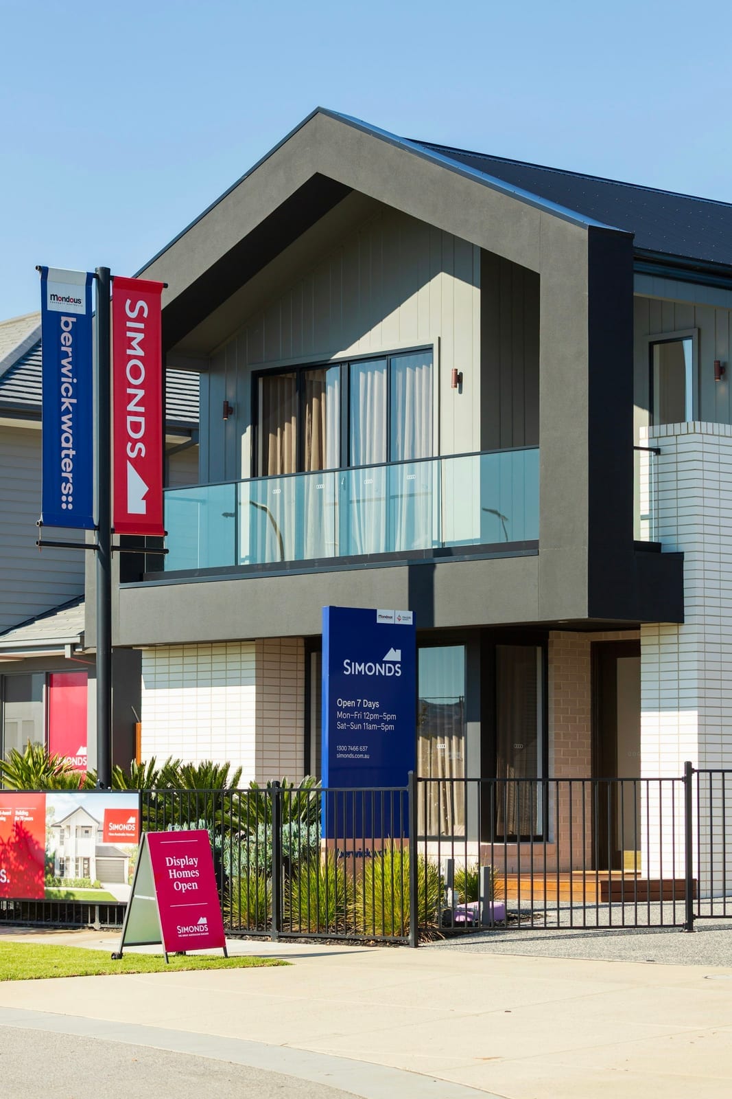 A modern Australian house with real estate signs and flags out the front