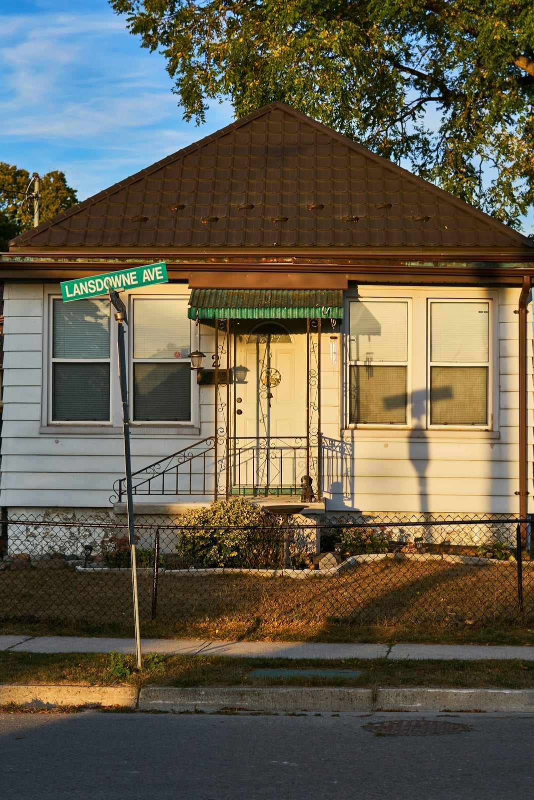 A small white house beside a street sign in a quiet neighborhood
