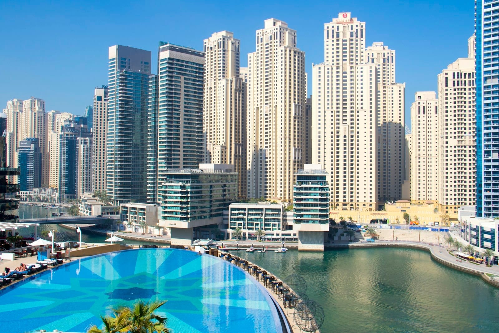 Dubai city towers seen behind a rooftop swimming pool on a clear day