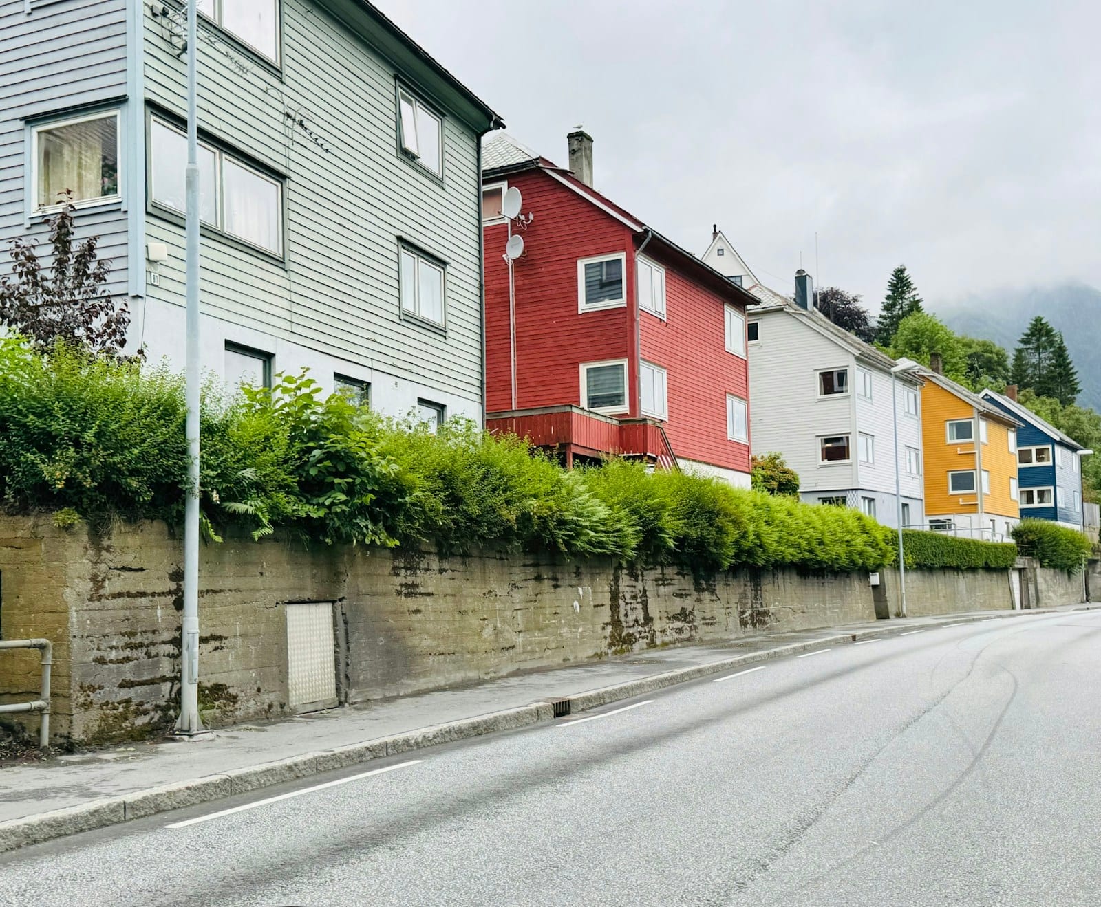 Colourful houses lining a street beside a stone wall