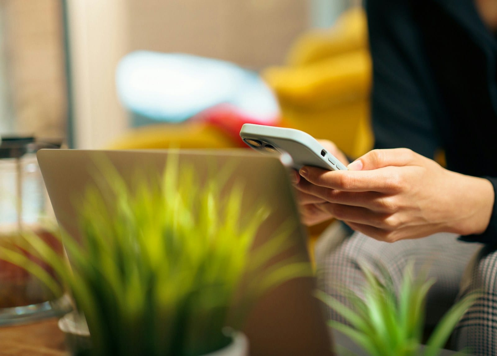 Someone using a phone next to an open laptop on a desk