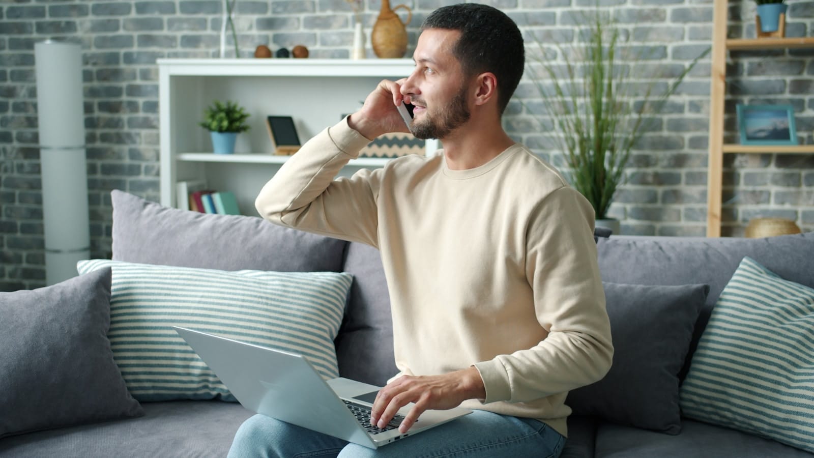 A man talking on the phone with a laptop resting on his lap