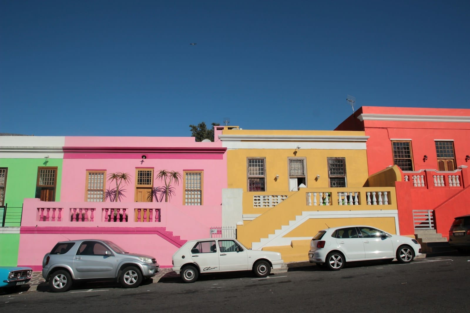 Cars parked in front of brightly coloured houses on a South African street