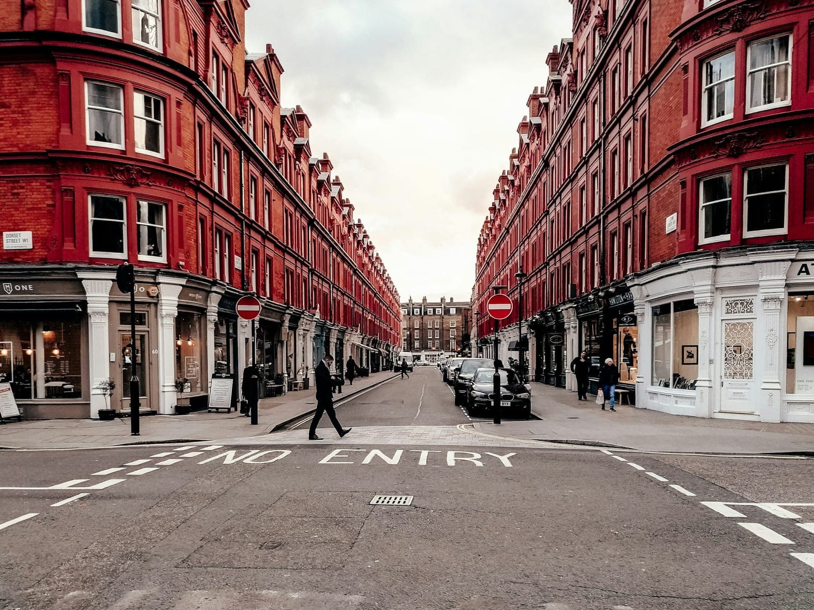 people walking on street between red concrete buildings during daytime